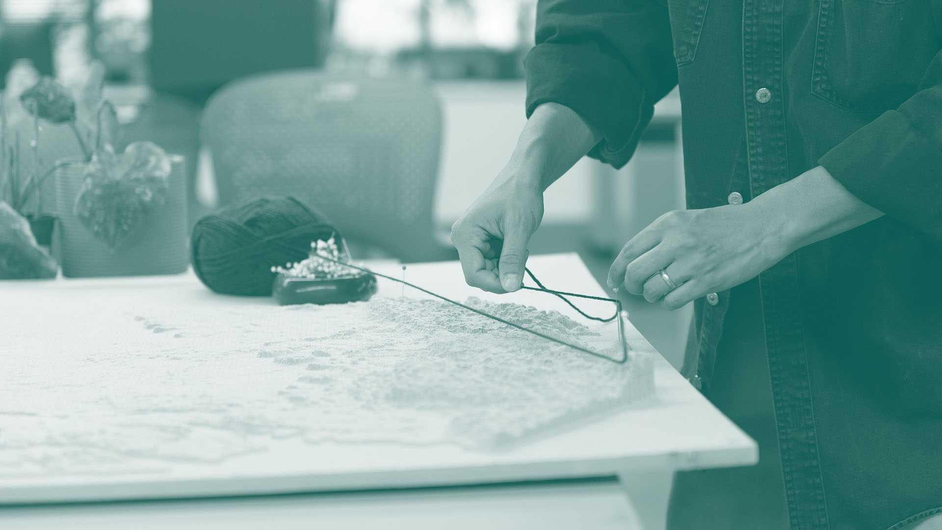 Student places yarn around pins on a topographical map.