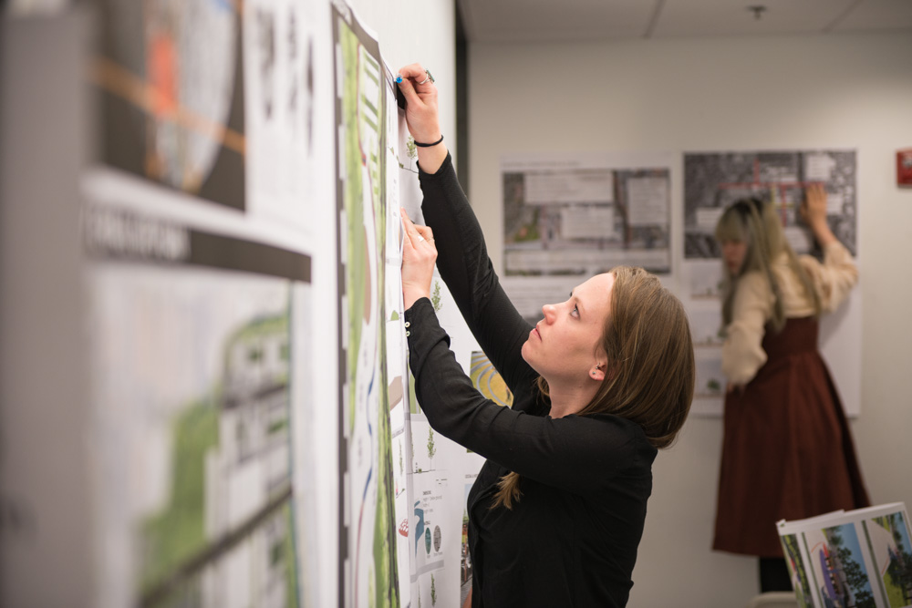 A female landscape architecture student hangs up drawings