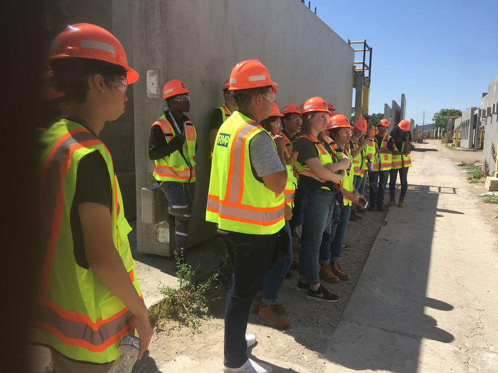 students in hard hats visiting a construction site