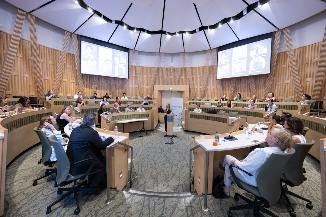 PeoplegatheredinacircularauditoriumwithNanEllinspeakinginthecenteroftheroom