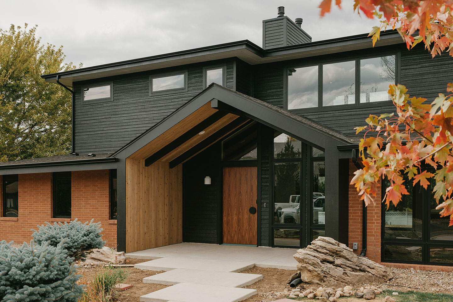 Exterior of a residence in Wheat Ridge, Colorado with black panels and red brick walls. 