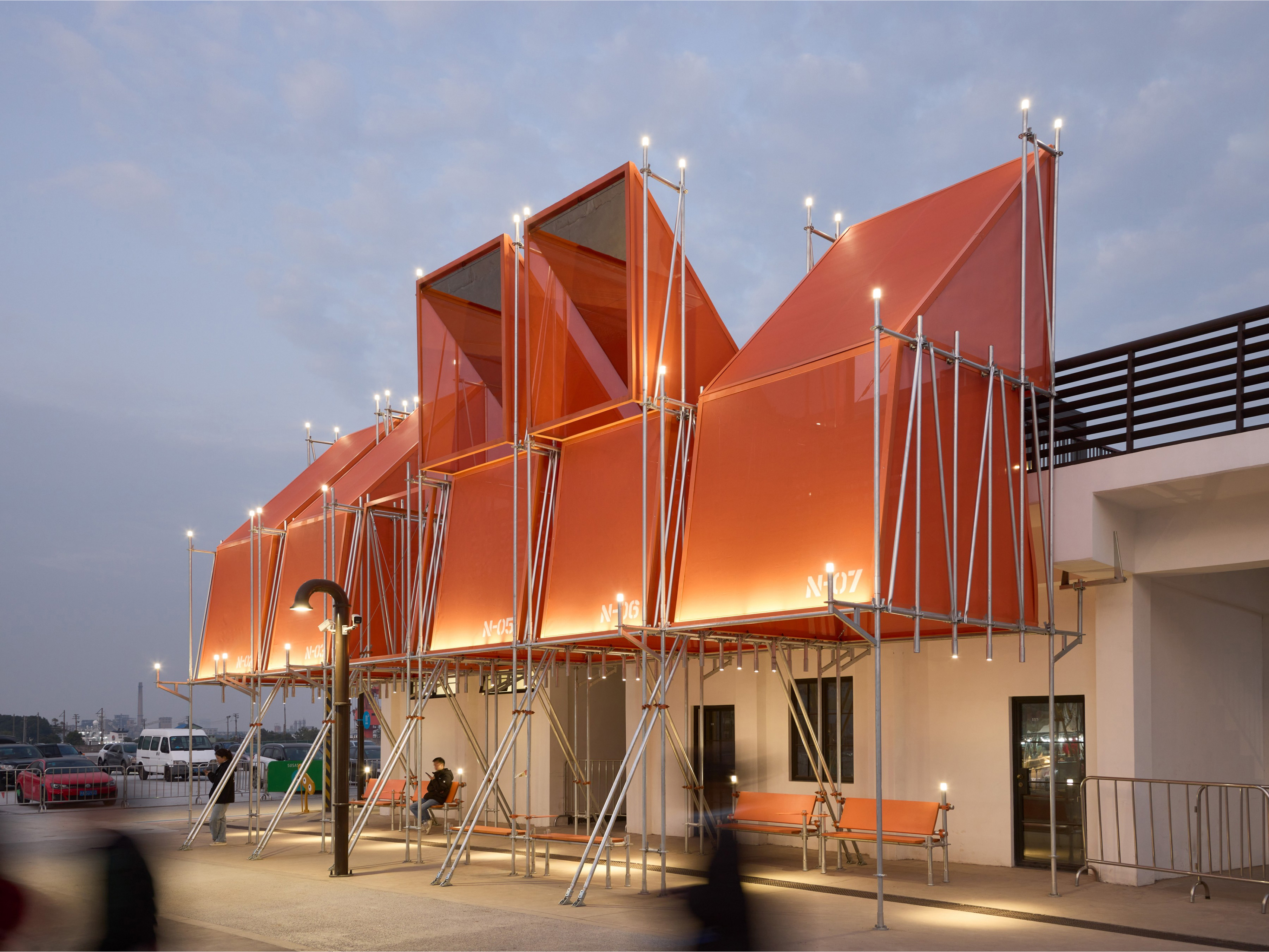 Installation at the Day of Laumching a project with an orange canopy with skylights and a person sitting under the awning.