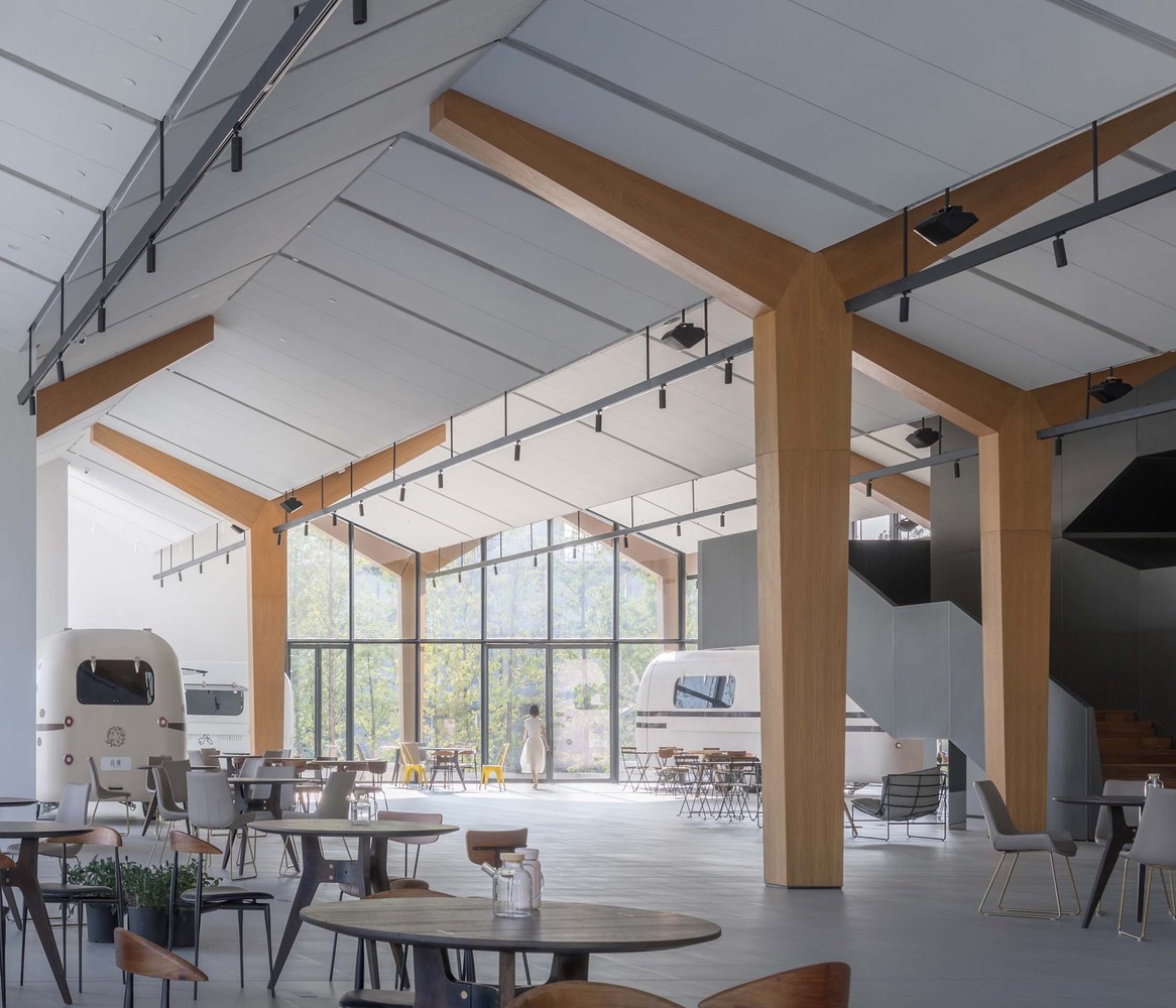 Interior of a careferia with lofted ceilings, tables and chairs and two Airstreams.