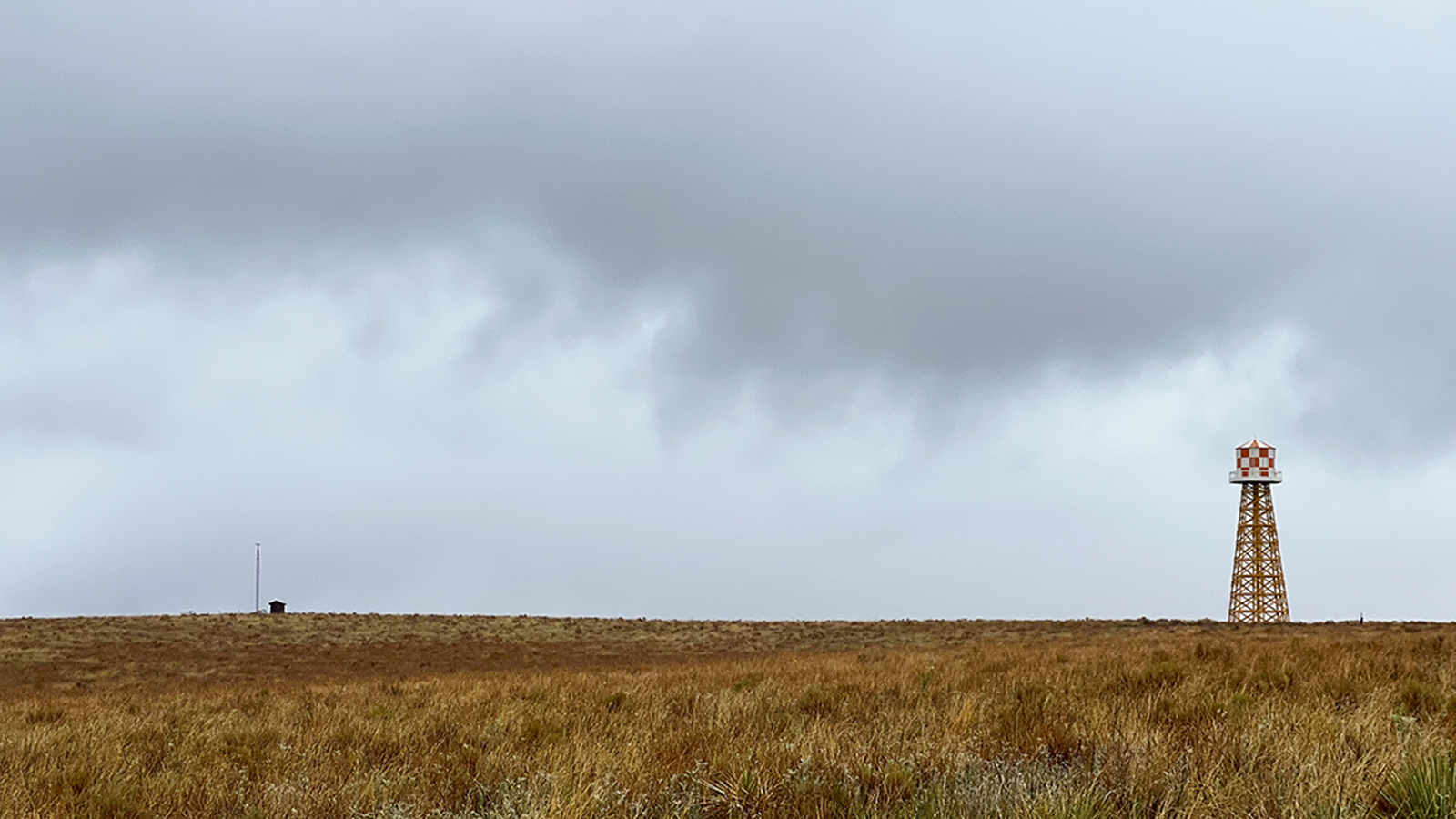 A field with a water tower on the Amache Historic Site.