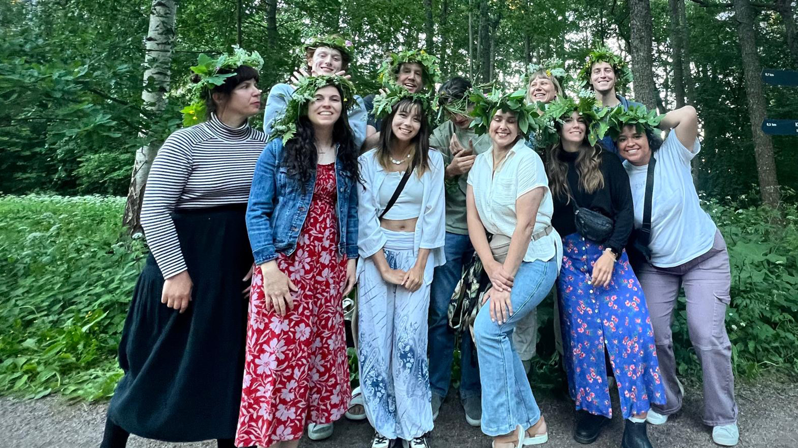 Eleven students post with floral crowns in a park for Midsummer in Finland.