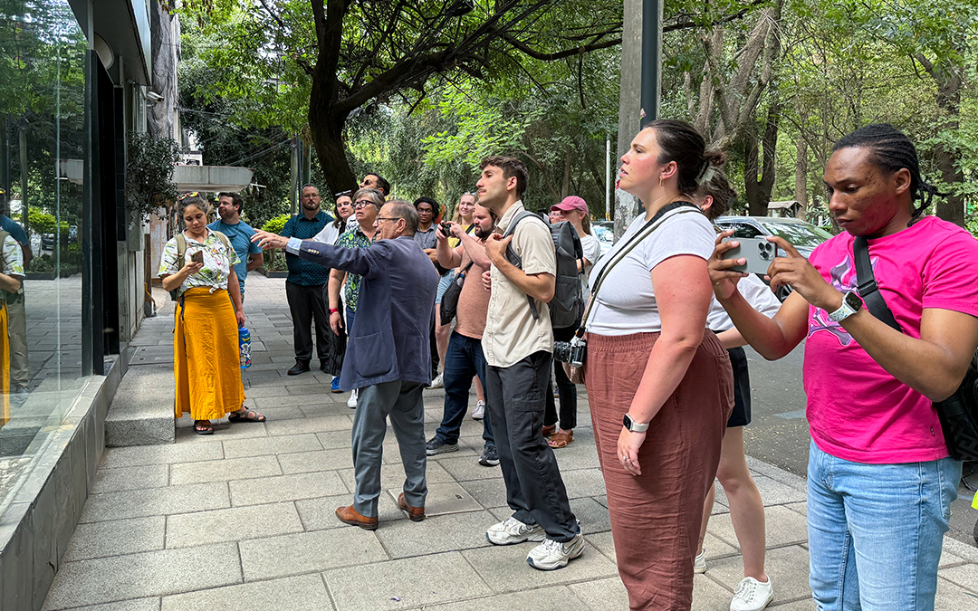 A tour guide points toward a feature of urban design in Mexico City.