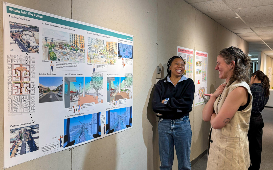 Two students laughing while discussing a poster posted on the wall.