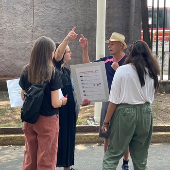 Four people talking about a poster and pointing.