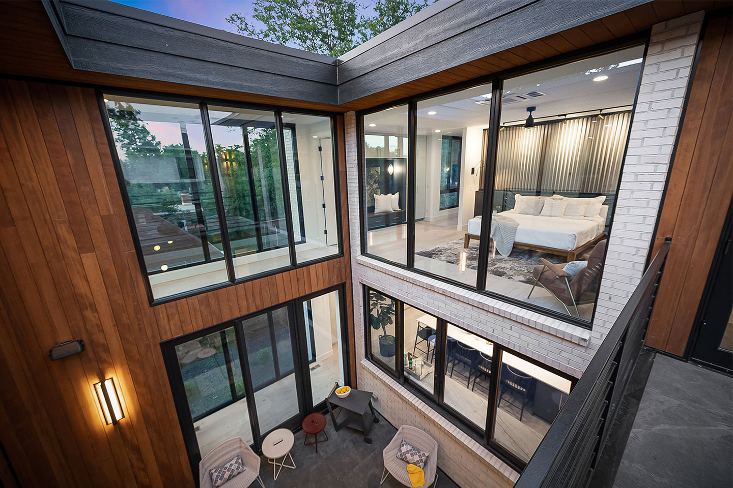 Adams Street Residence from an interior courtyard overlooking two levels the first floor including a sitting area and kitchen island and the second floor including a hallway and a bedroom. 