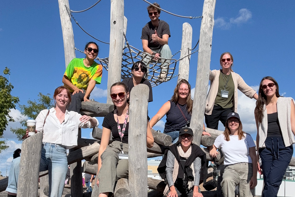A group of students and Lois Brink standing together on a jungle gym at a Toronto playground.