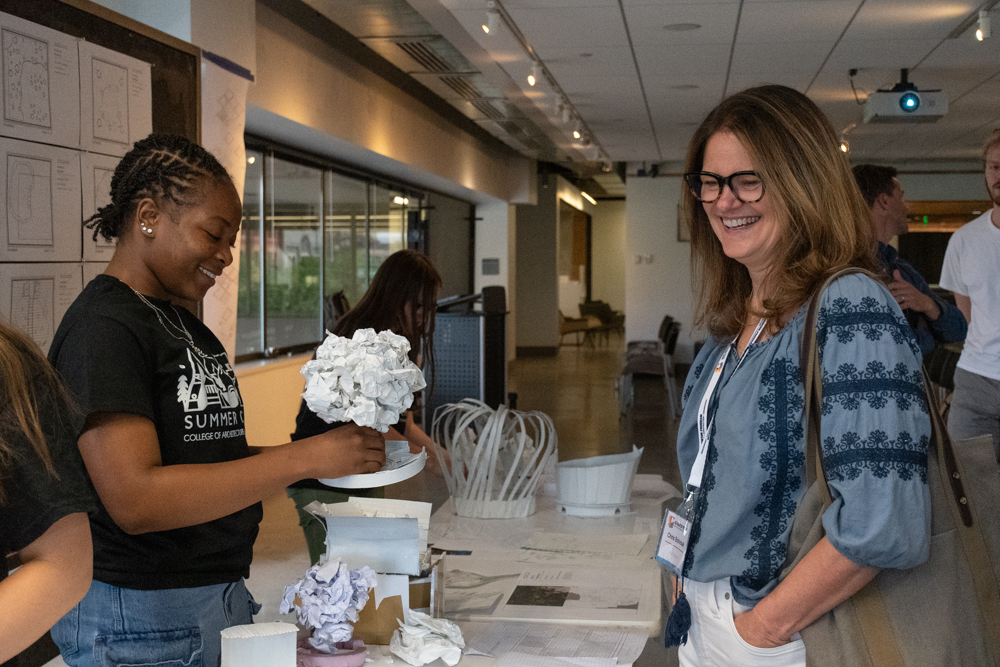 Student shows a guest reviewer her design of a paper tree at the ACE Summer Camp.