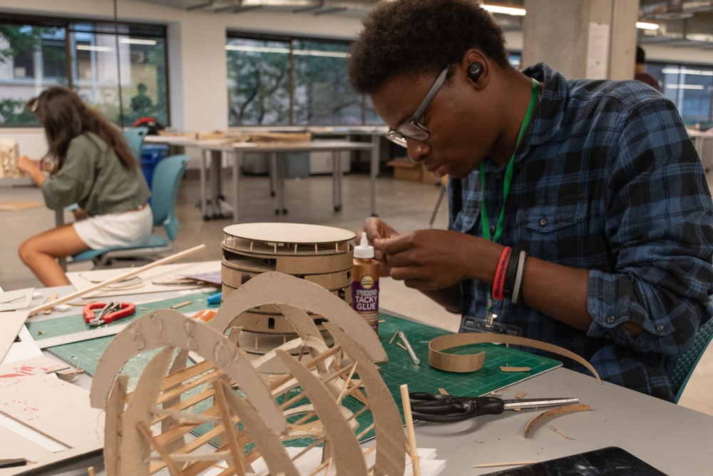 A student working on a project with supplies laying on the table in the studio.