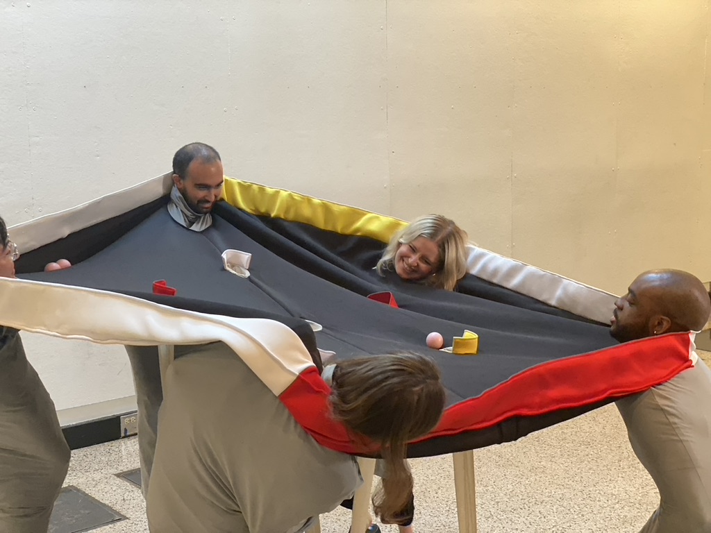 Four people wearing a fabric pool table.