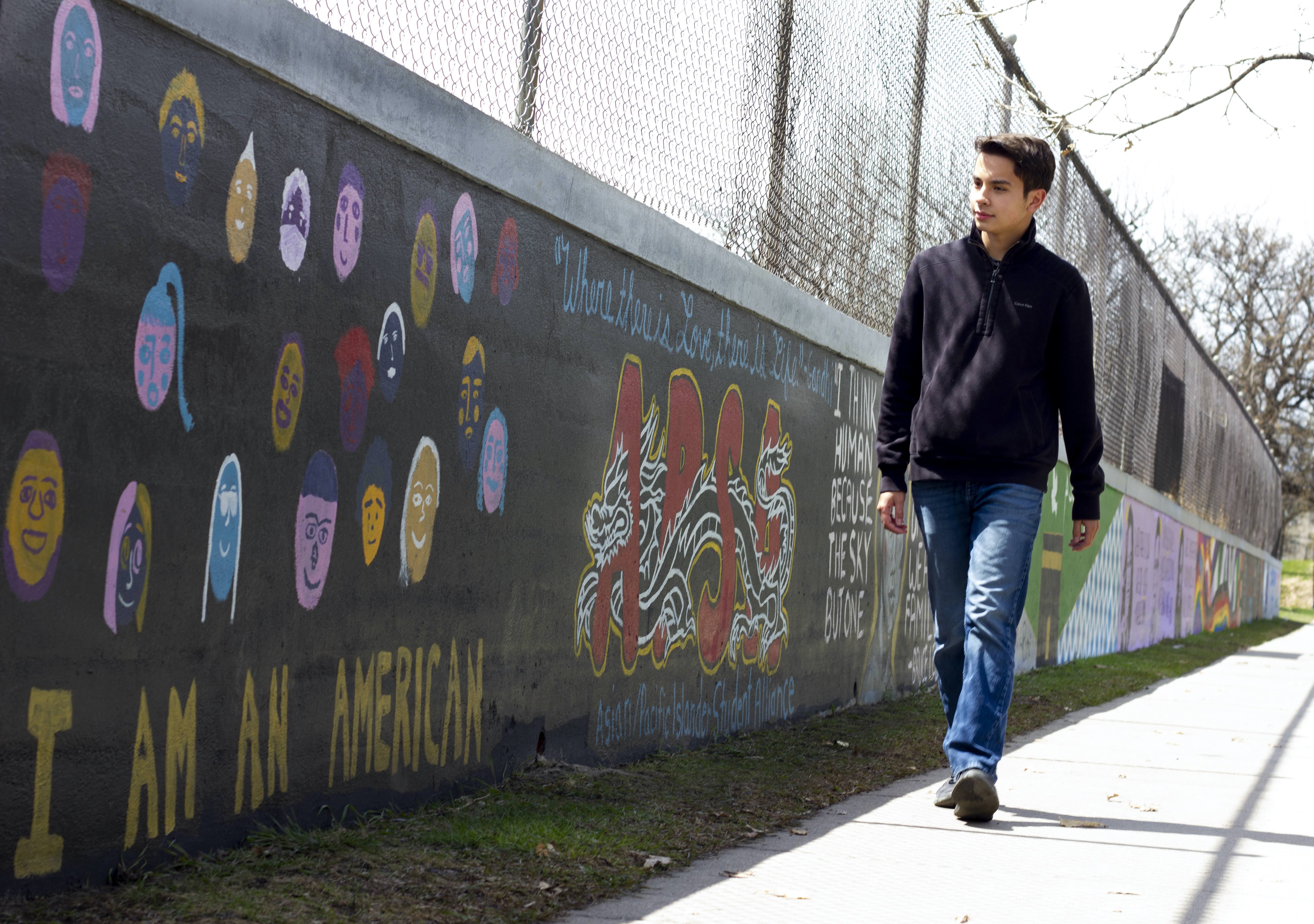 kai walking in front of mural