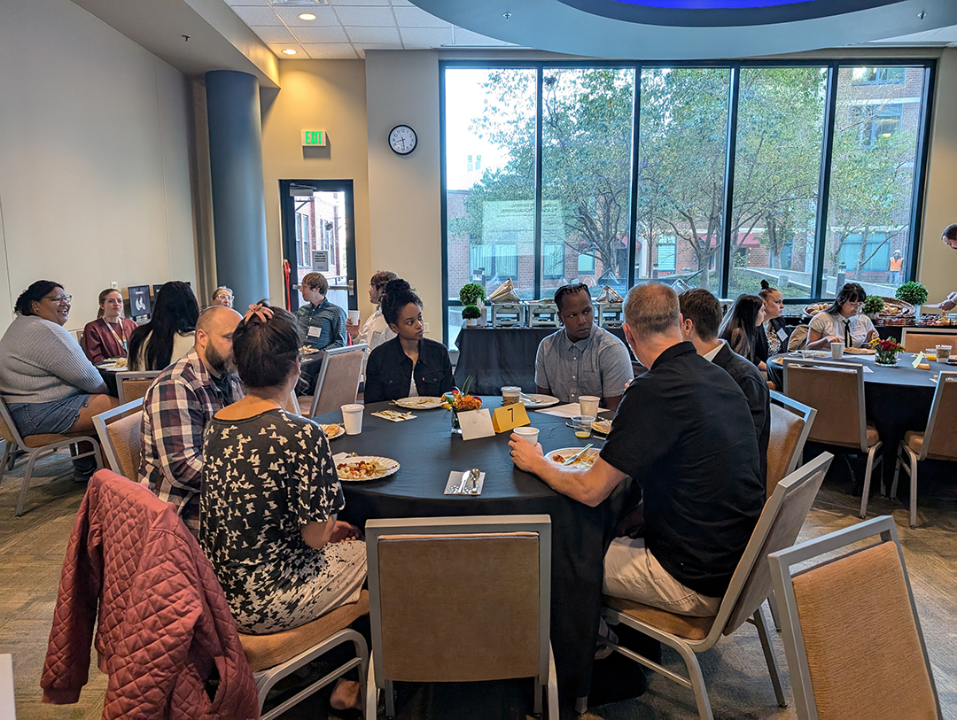 Students, donors, and faculty sitting around a table at the scholarship breakfast.