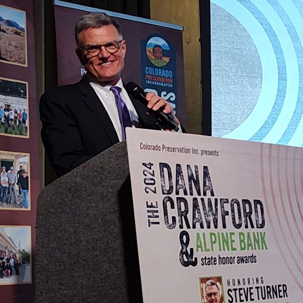 Steve Turner at a podium with the Dana Crawford banner