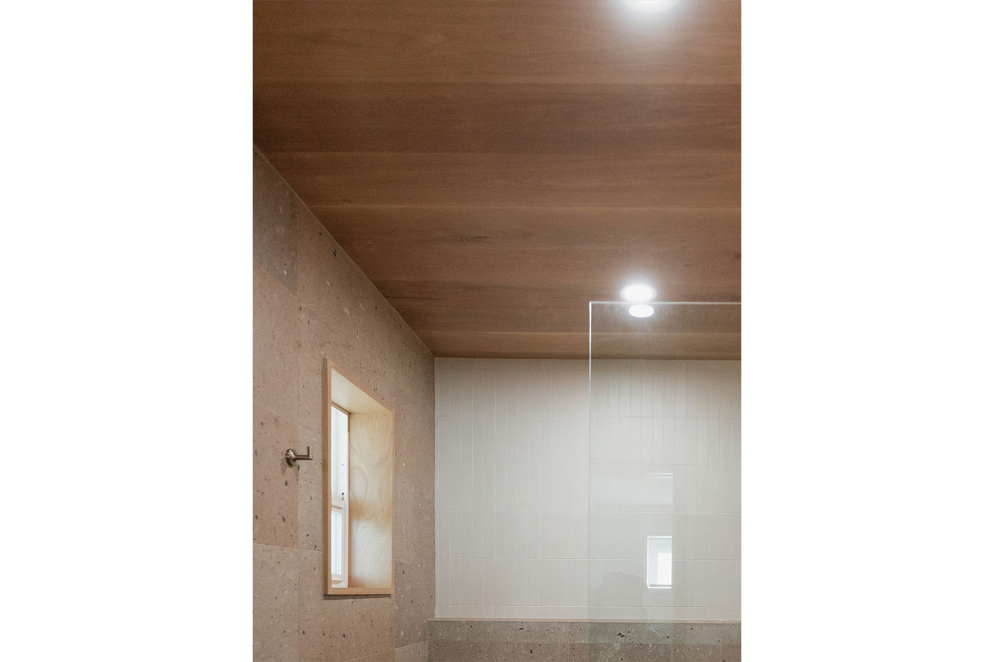 A bathroom with tile walls, a wooden ceiling, and a glass shower door.