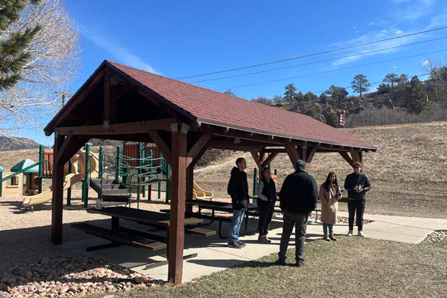 People standing around a pavilion at Wauconda Park on a chilly, sunny day.