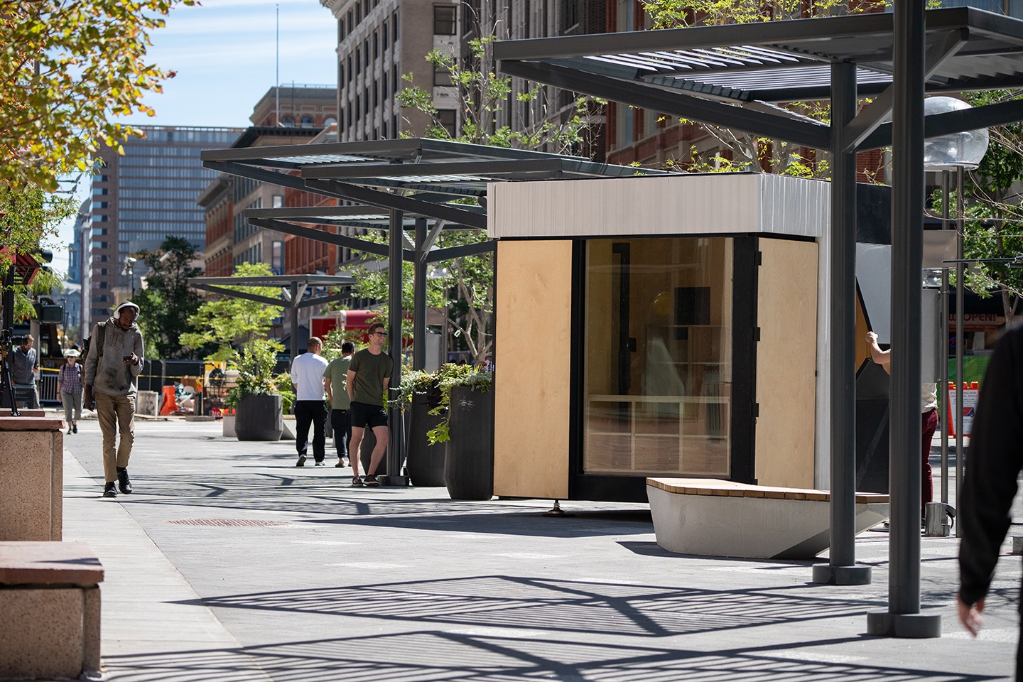 A kiosk along 16th Street with people walking by.