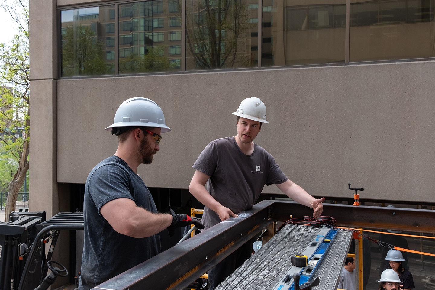 Two students collaborating on the roof of a kiosk.