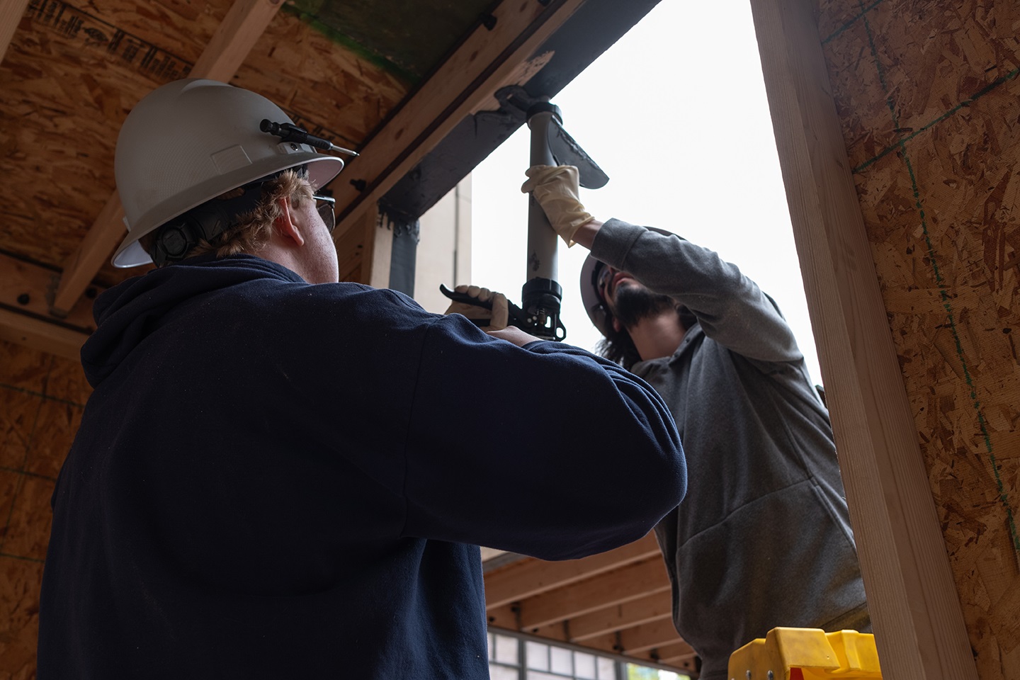 Two students measuring the windows of a kiosk.