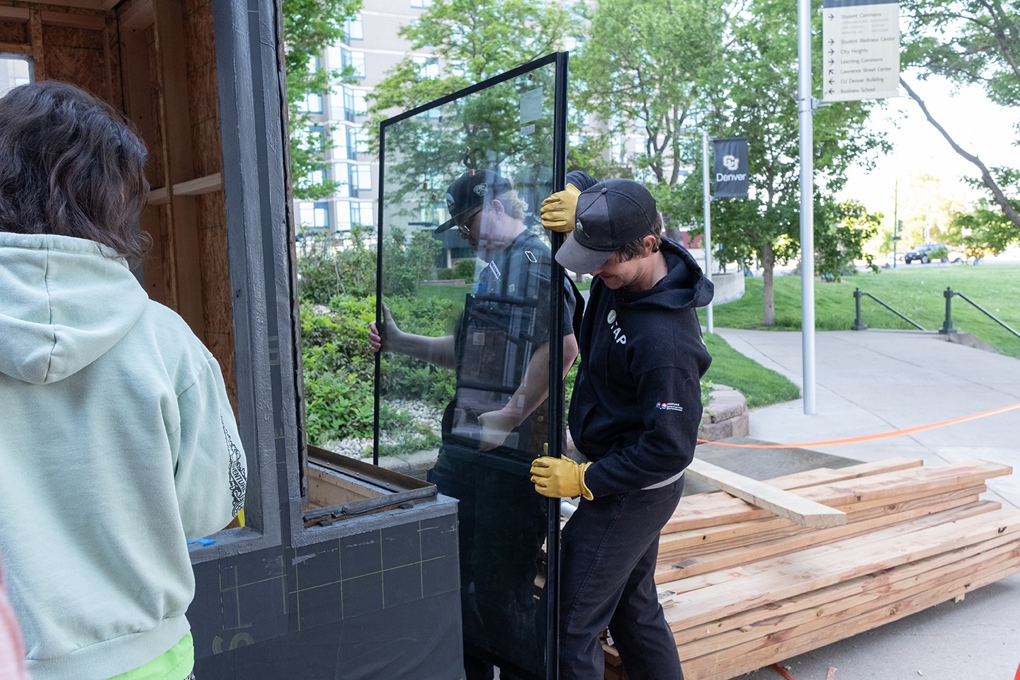 Three students installing windows for the kiosk.