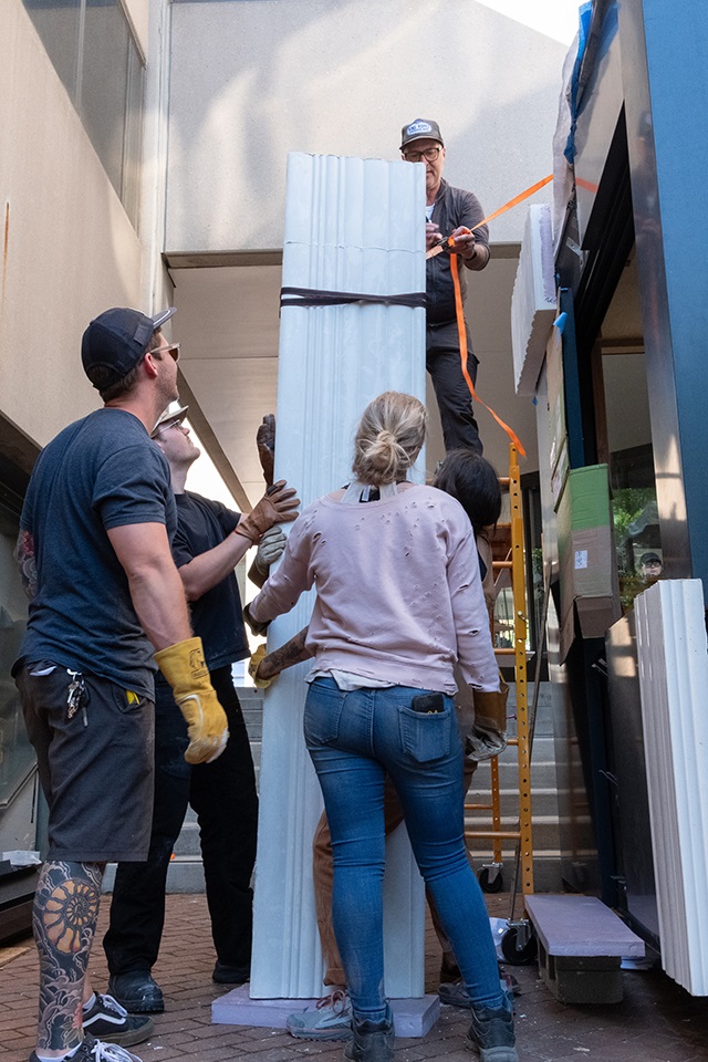 Students and faculty measuring the exterior wall of a kiosk.