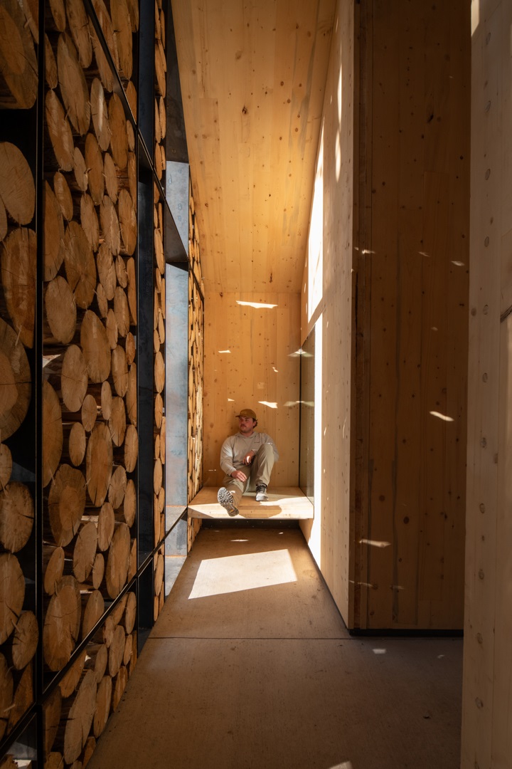 Interior of the Aiken Audubon Research Outpost focused on the open entry in the evening wth a student sitting on a bench.
