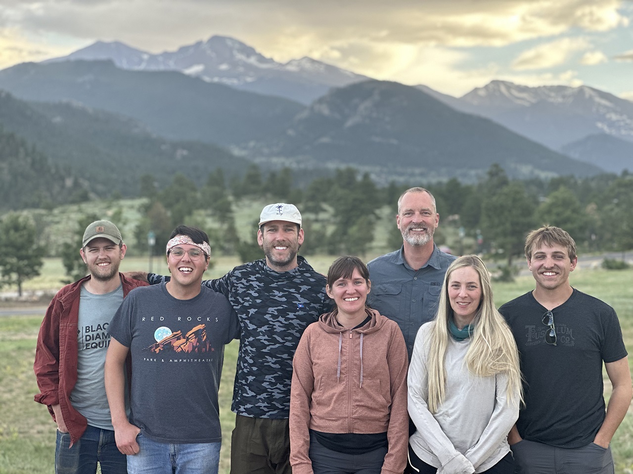 The Gem Lake Privy team standing together with the mountains and the sun setting in the background.