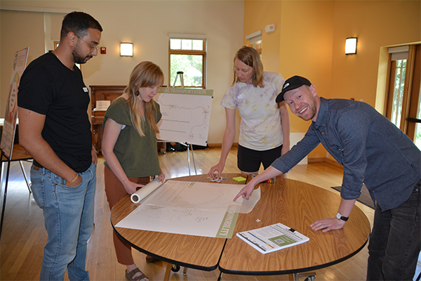 Four people at a table pointing to a map for a community engagement exercise.